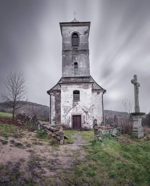 Vertical long exposure shot of old Church of Saint John of Nepomuk falling apart on a warm cloudy day of winter. Mysterious, atmospheric, scary place