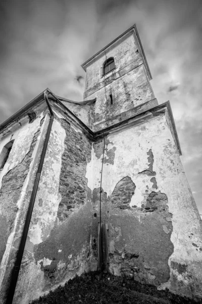 Vertical shot of old Church of Saint John of Nepomuk falling apart on a warm cloudy day of winter. Black and white image with dramatic low angle perspective. Mysterious, atmospheric, scary place