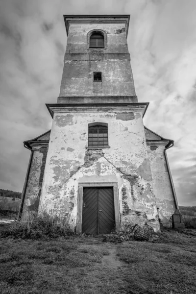 Vertical shot of old Church of Saint John of Nepomuk falling apart on a warm cloudy day of winter. Black and white image with dramatic low angle perspective. Mysterious, atmospheric, scary place