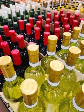 Şarap mahzeninde, şarap dükkanında ya da şarap deposunda ya da içki dükkanının arka planında renkli kapaklı şarap şişeleri. Alkol perakende ürünü. Kopyalama alanı olan bir şablon tasarla.