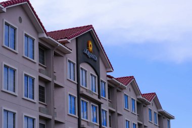 Üzerinde markanın logosu olan Sheraton Oteli ön cephesi parçalı bulutlu mavi gökyüzüne karşı..