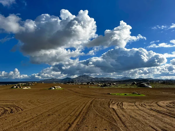 Open land farm field with beautiful clouds, mountains in the background