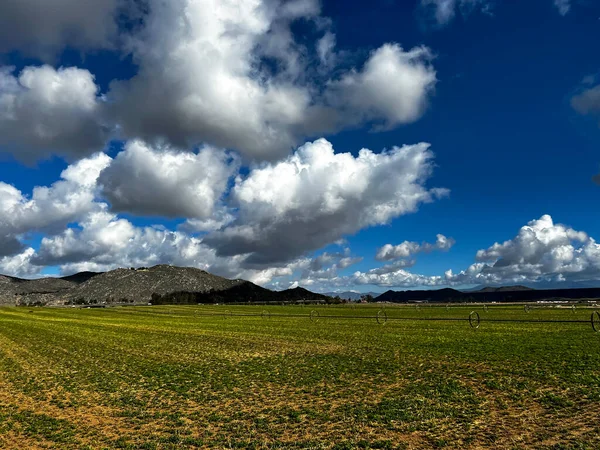 Open land farm field with beautiful clouds, mountains in the background