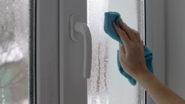 一个女人用毛巾擦拭玻璃窗上的冷凝物 穿上衣服4K镜头 — 图库视频影像