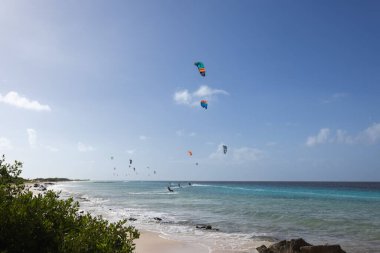 Sandy beach with turquoise water and kitesurfers on the horizon. Vacations on the tropics.