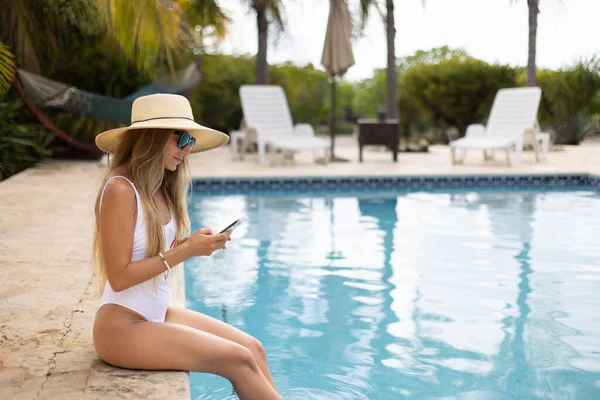 Dziewczyna Stroju Kąpielowym Kapeluszu Pomocą Telefonu Komórkowego Siedzi Relaksujący Pobliżu — Zdjęcie stockowe