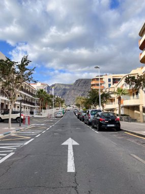 Üzerinde yol işareti olan bir yan yol. Paralel park etmiş arabaların olduğu cadde. Kimse yok..