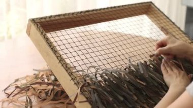 Woman weaving camouflage military mesh. Camouflage mesh for military helmet.