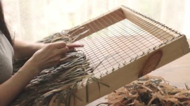 Woman weaving camouflage military mesh. Camouflage mesh for military helmet.