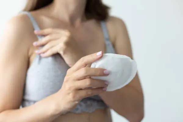 Süt damlamasını önlemek için meme için emici pedi olan bir kadın. Yakın çekim, seçici odaklanma
