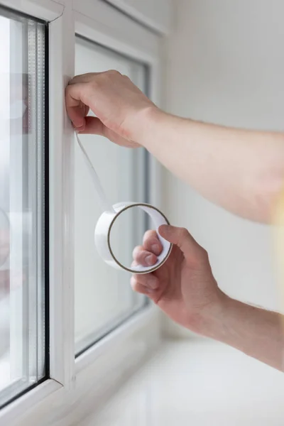 Adam pencereye askılı bant yapıştırıyor, taslaktan korunuyor.. 