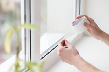 Penceredeki cereyan bandını tamir eden adam, taslaktan korunuyor.. 