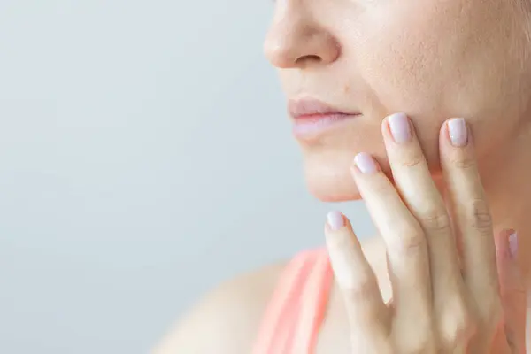 Dudağının üstünde ben olan kadın. Burun kırışıklıkları olan genç bir kadın. Derisi kuru ve yüzünde büyük gözenekleri var.. 