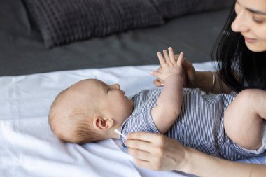 Gülümseyen anne bebeğinin kulaklarını temizliyor. Banyo yaptıktan sonra bebek hijyeni. 