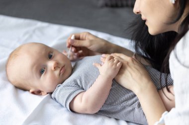 Anne bebeğinin kulaklarını temizliyor. Banyo yaptıktan sonra bebek hijyeni. Bebeğin portresi..