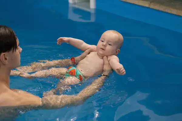 Swim coach teach a baby to floating backstroke