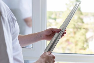 Pencereler için renkli film tutan bir adam.. 