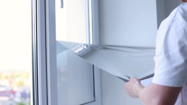 Adam pencerenin camından güneş koruma filmini alıyor. 4k görüntü