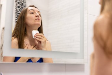 Kadın boynundaki kırışıklıkları düzeltmek için krem çubuğu kullanıyor. Ya da güneş kremi çubuğu.