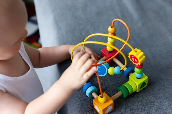 Yakın plan: küçük bir çocuk siparişleri öğreniyor, sıralıyor, rengarenk ahşap duyusal kısımlara göre düzenliyor. Eğitici oyuncaklar, bilişsel yetenekler, Montessori aktiviteleri. Seçici odak