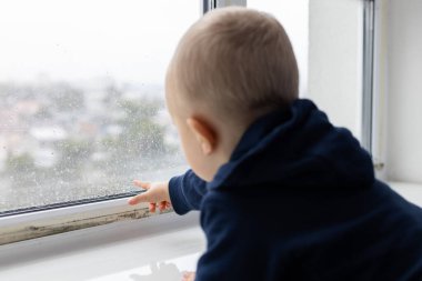 Pencere camındaki yoğunlaştırılmış su damlaları üzerinde küçük bir çocuk noktası. Penceredeki siyah küf mantarı lekeleri.