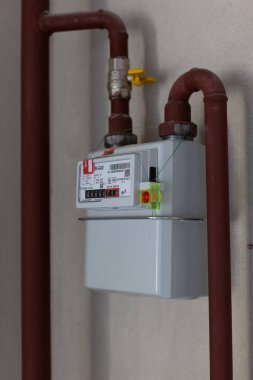 Borularla mühürlenmiş beyaz duvar gaz sayacı, yakın plan..