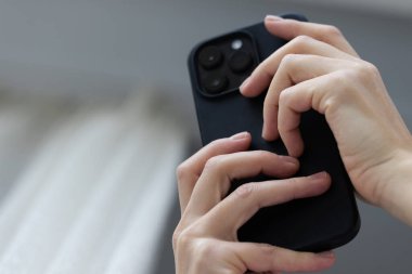 Kadın ellerinde siyah akıllı telefon. Düşük açı, yakın çekim.