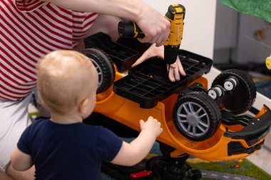 Baba oyuncak bir arabayı tornavidayla tamir ediyor.. 