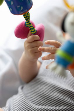 Yeni doğmuş bebeğin elleri tuhaf bir şekilde asılı oyuncaklarla oynuyor. Yakın çekim, seçici odaklanma