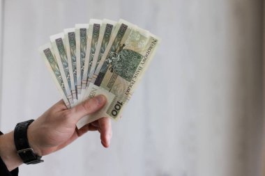 Polonyalı zloti banknotlarının 100 banknotundan vantilatör tutan adam. Yakın çekim..