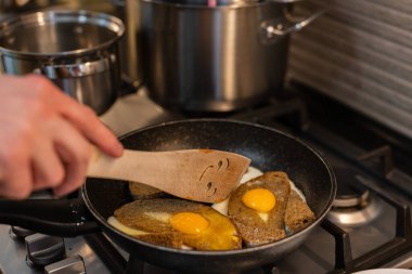 Adam kahvaltıda kızarmış yumurta ve kızarmış ekmek pişiriyor.