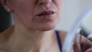 Aynanın önündeki kadın saçlarıyla üst dudağına bakıyor. İstenmeyen yüz kılı. . 
