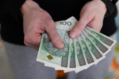 Polonya Zloti 'sinin 100 banknotunu elinde tutan adam. Yakın çekim.