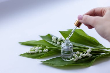 Kadın eli vadide cam bir şişe nilüfer yağı taşıyor. Yakın çekim.