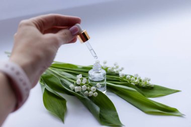 Kadın eli vadide cam bir şişe nilüfer yağı taşıyor. Yakın çekim.