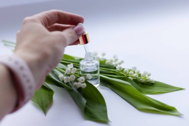 Kadın eli vadide cam bir şişe nilüfer yağı taşıyor. Seçici odak