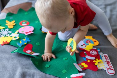 Oyuncak Noel ağacı olan küçük bir çocuk. Çocuklar için eğitici oyunlar