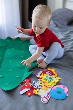 Noel ağacı oyuncağıyla küçük bir çocuk. Çocuklar için eğitici oyunlar