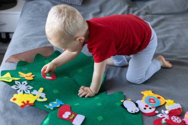 Oyuncak Noel ağacı olan küçük bir çocuk. Çocuklar için eğitici oyunlar