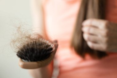 Sağlıklı bir kavram. Kadın fırçasını uzun saçlarıyla gösteriyor. Yakın çekim, seçici odaklanma