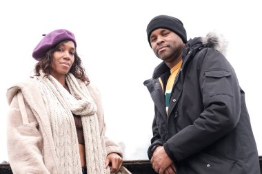 İki işitme engelli arkadaş dışarıda kameraya bakıyor. Soğuk bir kış günü ve ikisi de palto giyiyor..