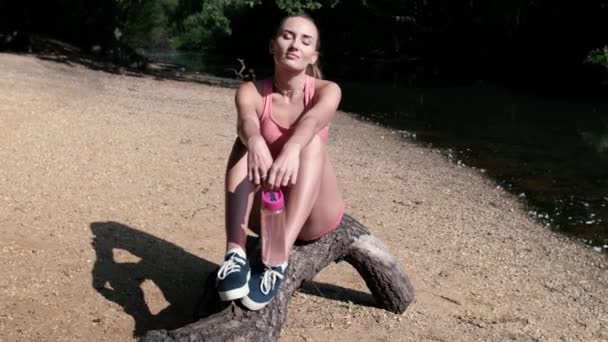 스포츠를 즐기는 여자가 일광을 즐기는 통나무 그녀는 런던에 호수의 기슭에 — 비디오
