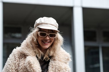 Smiling woman model is posing in a London street in a cold winter day. She has an alternative edgy look and she looks happy.