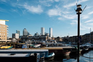 Arkasında Canary Wharf olan Limehouse Havzası gemilerinin görüntüsü. Ön tarafta bir sokak lambası ve havzada bir sürü gemi var..