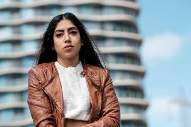 Dışarıdaki kameraya bakan kendine güvenen Hintli kadın. Arkasında çok modern bir bina var..