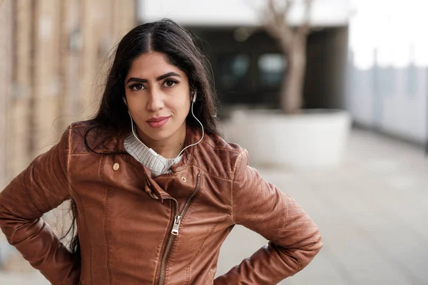 stock image Portrait of young indian woman using headphones outdoors. She is looking at camera.