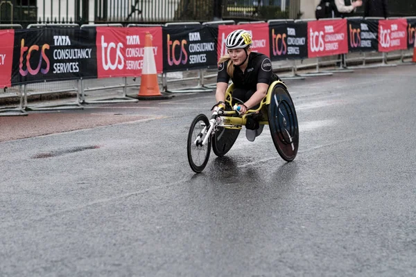 Londra, İngiltere Nisan-20-2023. Maraton, engelli, tekerlekli sandalyede gülümseyen bir kadın yağmur altında katılıyor. Üstesinden gelme ve dayanıklılık kavramı.