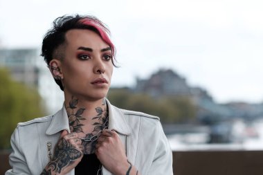 Açık havada beyaz deri ceketini tutan çift cinsiyetli bir erkeğin klasik portresi. Lgbt ve çeşitlilik kavramı.