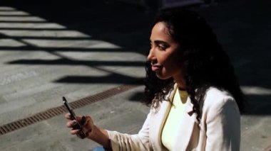 Dışarıda telefonunda yazan gülümseyen genç bir kadın. Gölgeler arasındaki iletişim ve teknoloji konsepti portresi.