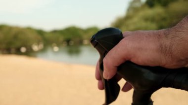 Bisikletçinin el frenini çekerken çekilmiş yakın çekim videosu. Arkada bir göl var ve bazı bulanık kuşlar uçuyor..